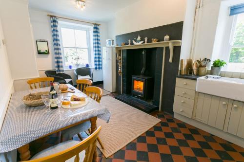 a kitchen and living room with a table and a fireplace at Bears Cottage in Moelfre