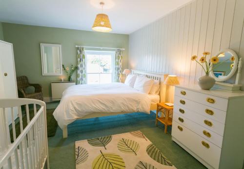 a bedroom with a white bed and a white dresser at Bears Cottage in Moelfre