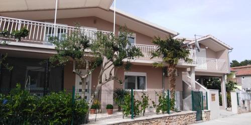 a pink house with palm trees in front of it at Apartments Anita Frane in Vodice