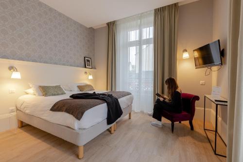 une femme assise dans une chaise rouge dans une chambre d'hôtel dans l'établissement La Maison Blanche - AppartHôtels de charme Chic & Cosy à 350m du cœur de ville de Limoges - Accès autonome, à Limoges