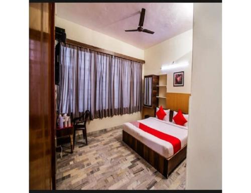 a bedroom with a bed with red pillows and a desk at HOTEL SANDS INN, Jodhpur in Jodhpur