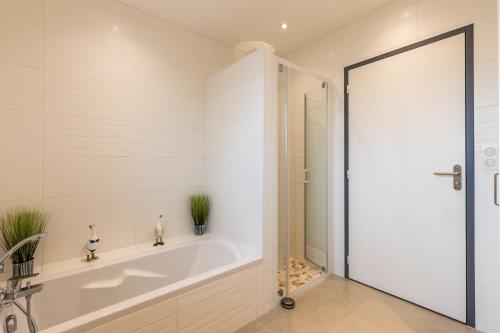 ein weißes Bad mit einer Badewanne und einer Dusche in der Unterkunft Bassin d'arcachon in Arès