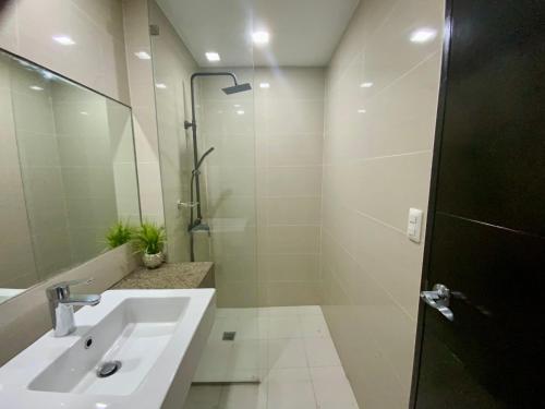 ein weißes Bad mit einem Waschbecken und einer Dusche in der Unterkunft Gorgeous One Eastwood Ave Suite in Manila