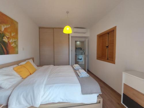 una camera da letto con un grande letto bianco con cuscini gialli di Palm Beach Apartment 26 a Limassol