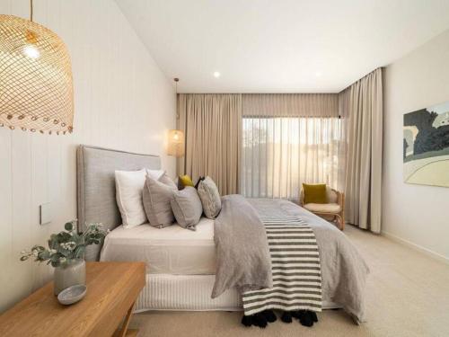 a bedroom with a bed with pillows and a table at LUXE Poolside living, in the heart of Flinders in Flinders