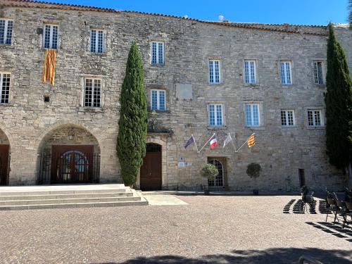 - un grand bâtiment en pierre avec des drapeaux devant dans l'établissement L'OUSTAOU BELLO VISTO, au Castellet