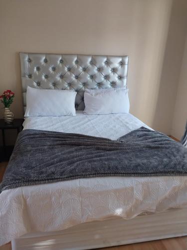a large bed with a gray blanket and pillows at Home Life Guesthouse in Midrand