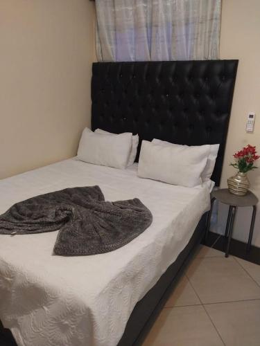 a bed with a black headboard and a blanket on it at Home Life Guesthouse in Midrand