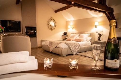 a bedroom with a bed and a table with a bottle of wine at Duo Détente in Le Chenoy