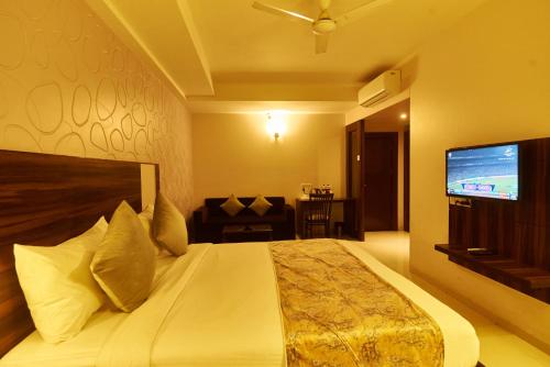 a bedroom with a large bed with a tv on the wall at Hotel G-Square - Shirdi in Shirdi