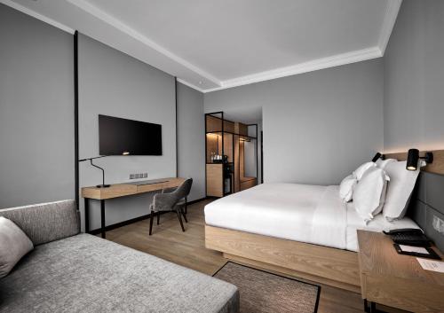 a bedroom with a bed and a desk and a tv at AC Hotel by Marriott Penang in Bayan Lepas