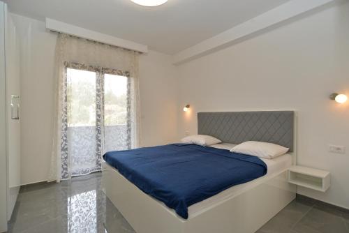 una camera bianca con un letto con lenzuola blu e una finestra di Apartments Djordjo 2295 a Banjole
