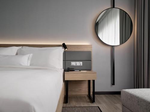 AC Hotel by Marriott Penang في بايان ليباس: غرفة نوم مع سرير ومرآة على الحائط
