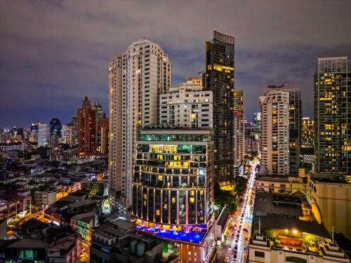 a city lit up at night with tall buildings at Valia Hotel Bangkok in Bangkok
