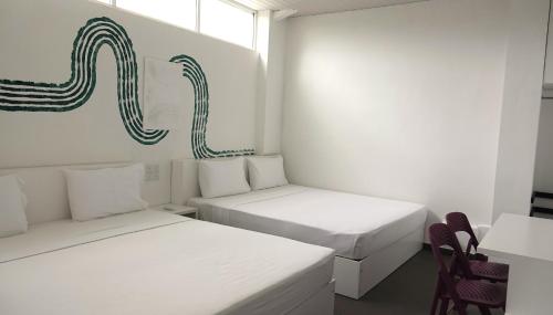 ein weißes Zimmer mit 2 Betten und einem Stuhl in der Unterkunft City Beds Negombo in Negombo