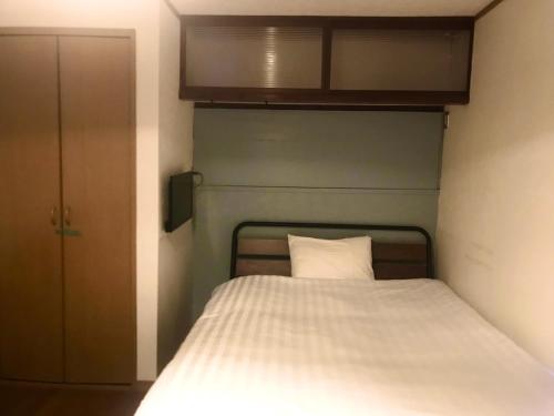 a small bedroom with a bed with a white pillow at NOW TRAVEL ShinOsaka in Osaka