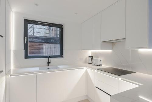 a white kitchen with a sink and a window at Blue Jeans White Shirt - Fitzrovia - by Frankie Says in London