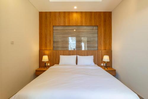 een slaapkamer met een groot wit bed met 2 lampen bij Astungkara Bali Villa in Tabanan