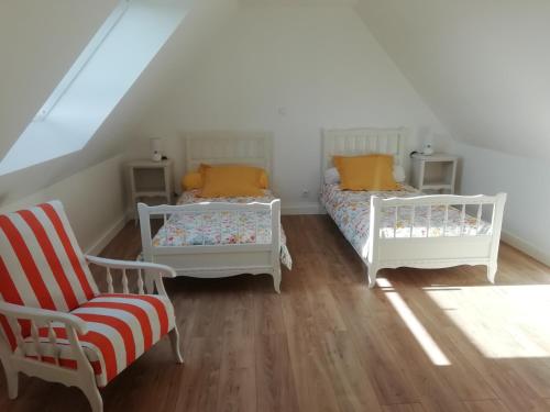 2 Betten und ein Stuhl in einem Zimmer mit Dachgeschoss in der Unterkunft Gîte Ty Loguellou in Locmélar