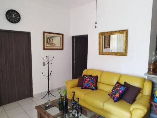 uma sala de estar com um sofá amarelo e uma mesa em Renta de cuartos por dia em Ameca