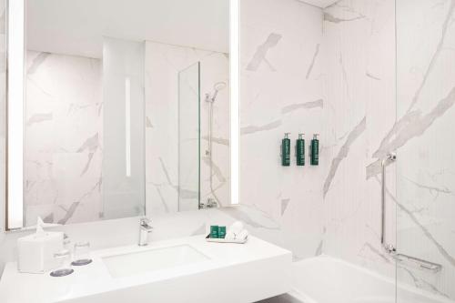 Doubletree By Hilton Fujairah City في الفجيرة: حمام أبيض مع حوض ودش