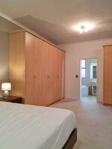 a bedroom with a white bed and wooden cabinets at Island Club by Smart City Stays in Cape Town