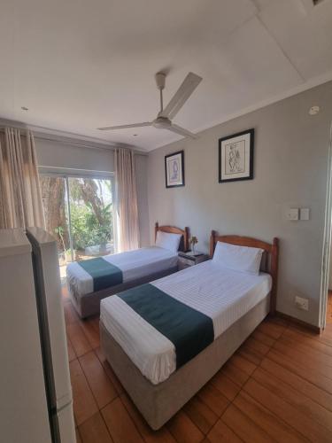 two beds in a hotel room with a window at Bonnie Highlands in Ladysmith