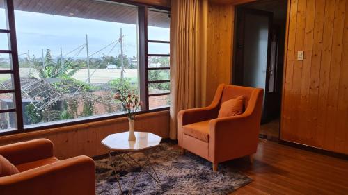 a living room with two chairs and a large window at An Nhiên Villa in Bao Loc