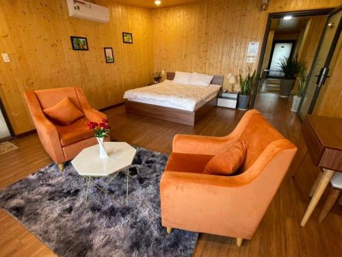 a bedroom with a bed and two chairs and a table at An Nhiên Villa in Bao Loc