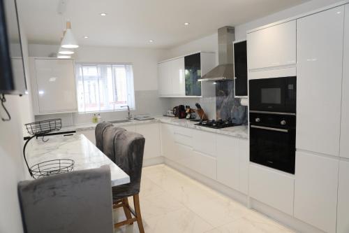 a kitchen with white cabinets and a table with chairs at Vienna Orpington in Orpington