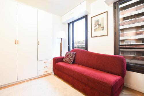 - un canapé rouge dans une chambre avec fenêtre dans l'établissement GuestReady - Studio lumineux à Folie-Méricourt, à Paris