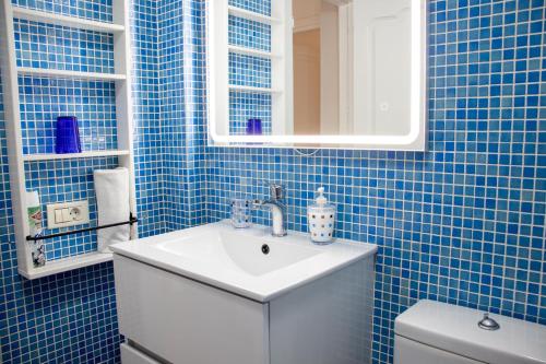 baño de azulejos azules con lavabo y aseo en HD Mogan Beach Apartment, en Puerto de Mogán