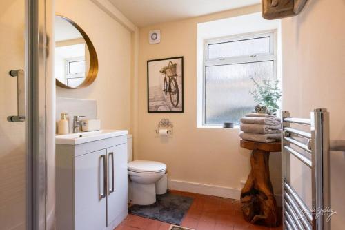 a bathroom with a toilet and a sink and a window at Cosy Cottage in Heart of Glossop in Glossop