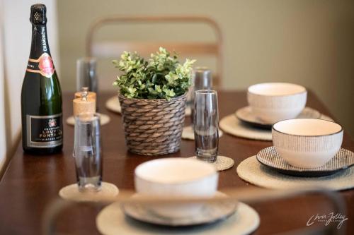 a table with plates and a bottle of champagne and a plant at Cosy Cottage in Heart of Glossop in Glossop