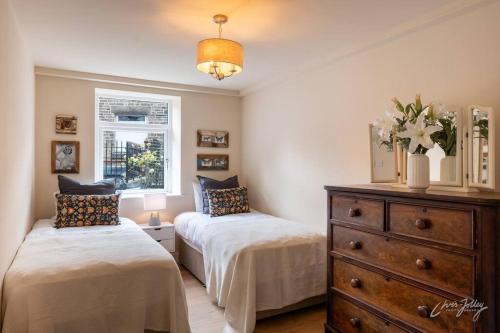 a bedroom with two beds and a dresser and a window at Cosy, Cottage Style Apartment in Peak District in Glossop