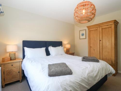 um quarto com uma grande cama branca e um lustre em Llwyn Onn em Pwllheli