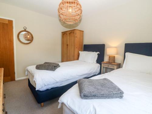 a bedroom with two beds and a chandelier at Llwyn Onn in Pwllheli