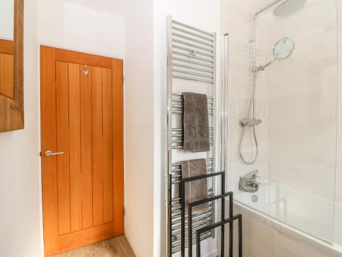uma casa de banho com um chuveiro e uma porta de madeira em Llwyn Onn em Pwllheli