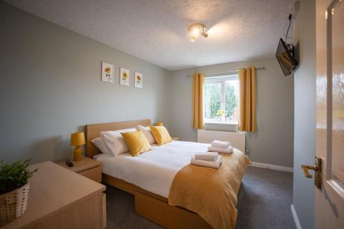 a bedroom with a bed with towels on it at Woodpecker House By RentMyHouse in Hereford