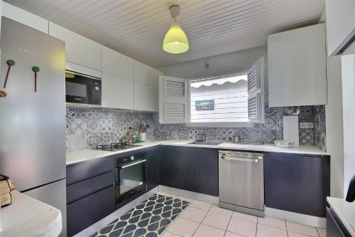 una cocina con armarios blancos y azules y una ventana en Villa du Morne d'Orange - Grande piscine, vue exceptionnelle sur St Pierre, plage à 5min en Saint-Pierre