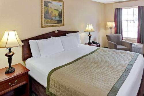 a hotel room with a large bed and a chair at Baymont by Wyndham Sanford in Sanford
