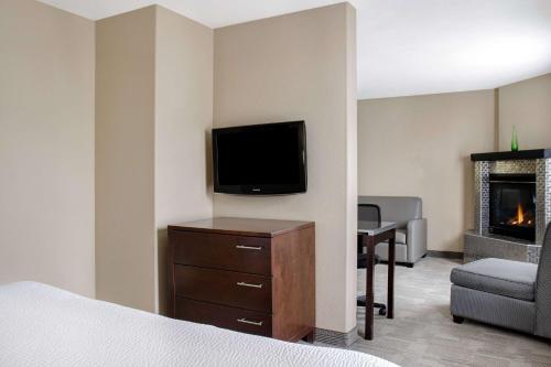 a hotel room with a bed and a television and a chair at Days Inn by Wyndham Medicine Hat in Medicine Hat