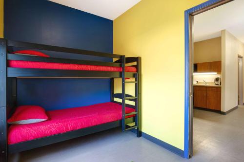 a room with two bunk beds with red sheets at Days Inn by Wyndham Medicine Hat in Medicine Hat