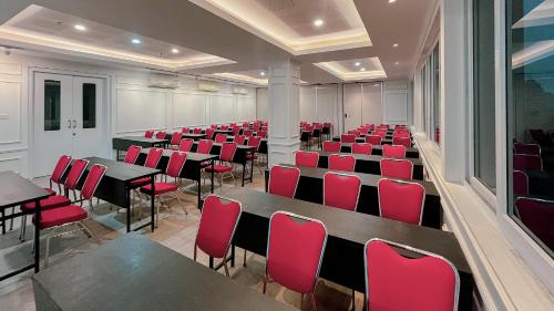 une chambre avec des tables, des chaises et des chaises rouges dans l'établissement The Win Hotel Surabaya, à Surabaya