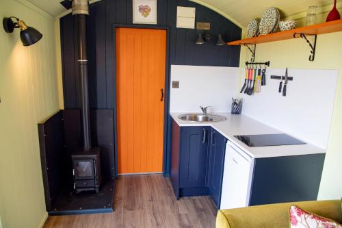 a kitchen with an orange door and a sink at The Gambo Shepherd's Hut in Kidwelly