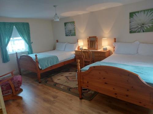 1 dormitorio con 2 camas y mesa con espejo en Drumaneir Cottage en Carrickmore