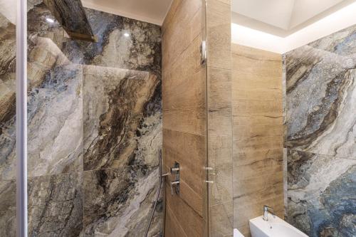 y baño con ducha y pared de piedra. en Mary’s Guest House, en Vico Equense