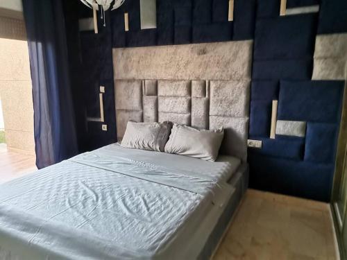 Schlafzimmer mit einem Bett mit blauem Kopfteil in der Unterkunft très belle maison avec jardin et piscine in Saidia 