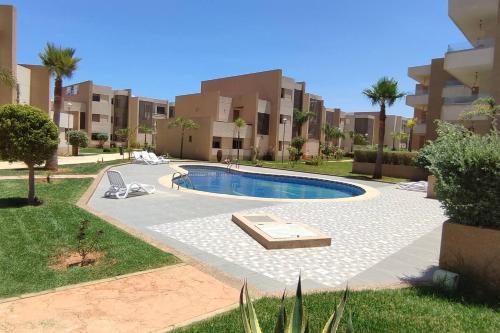 una piscina frente a algunos edificios de apartamentos en très belle maison avec jardin et piscine, en Saidia 