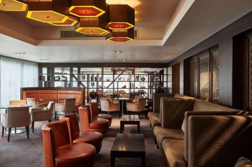 a restaurant with brown chairs and tables and a chandelier at DoubleTree by Hilton London Ealing in London
